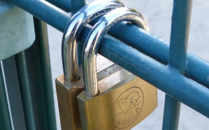 Brass padlock locked onto a blue metal railing