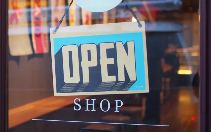 Shop owner checking orders and customer emails on a laptop