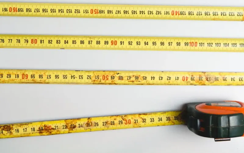 Yellow tape measures laid side by side on a white workbench