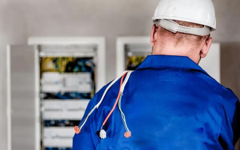 Engineer in a white hard hat working at an electrical cabinet